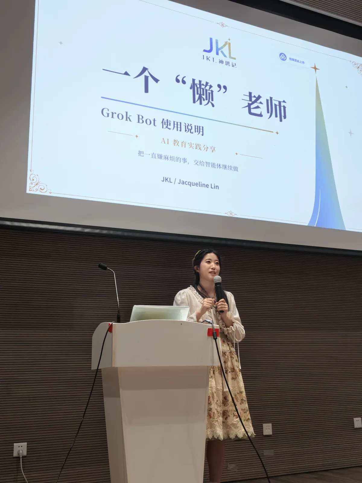 JKL 在台上开讲，身后大屏是开场页「一个"懒"老师 · Grok Bot 使用说明」